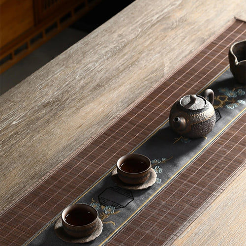 Chemin de table en bambou marron dressé avec une théière et deux bols à thé