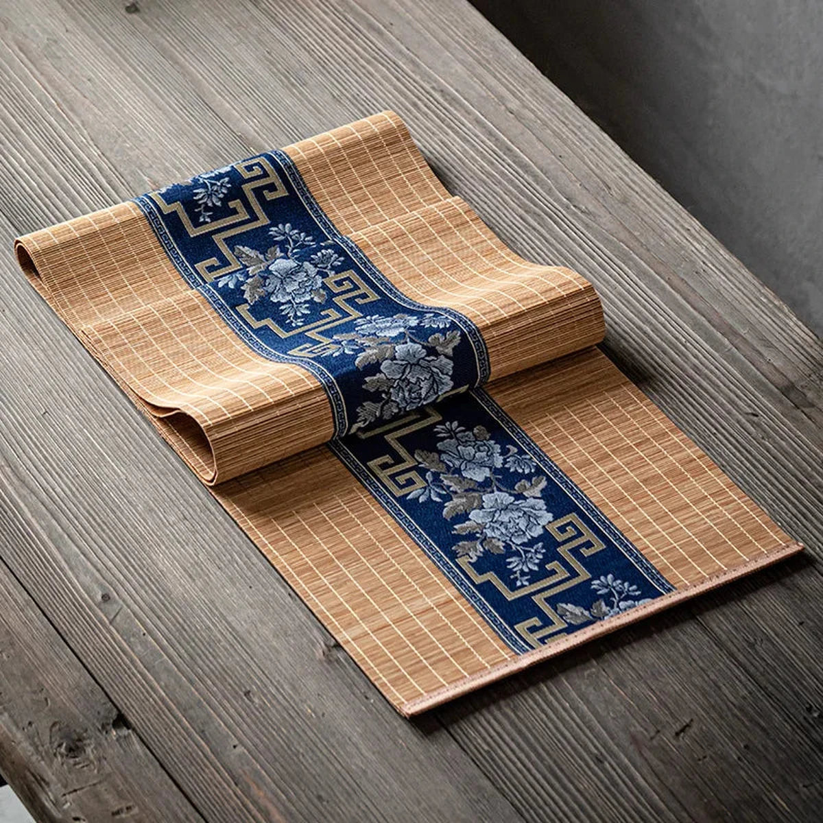 Chemin de table en bambou naturel à bandeau bleu porcelaine, posé sur une table en bois