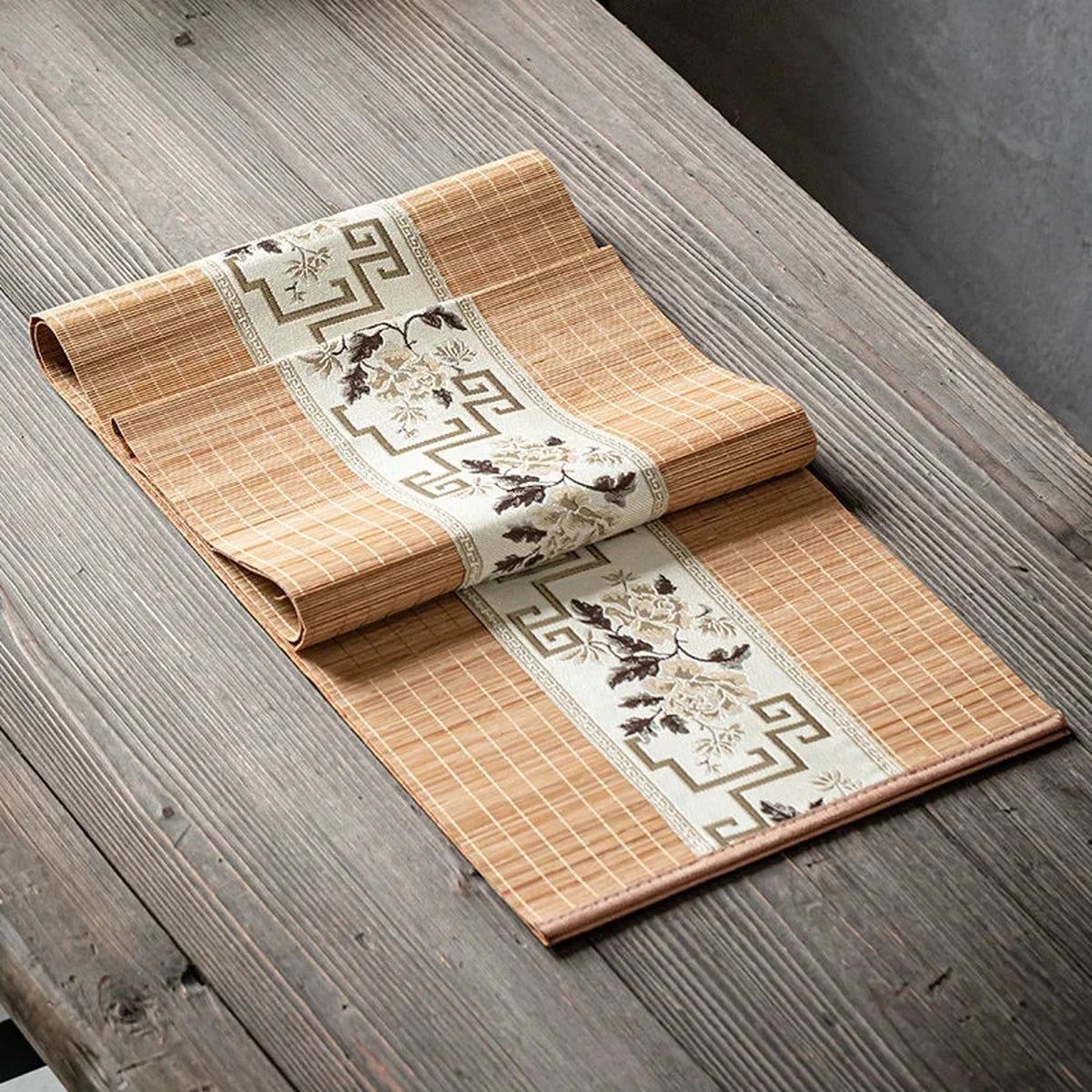 Chemin de table en bambou naturel à bandeau fleuri taupe, sur une table en bois