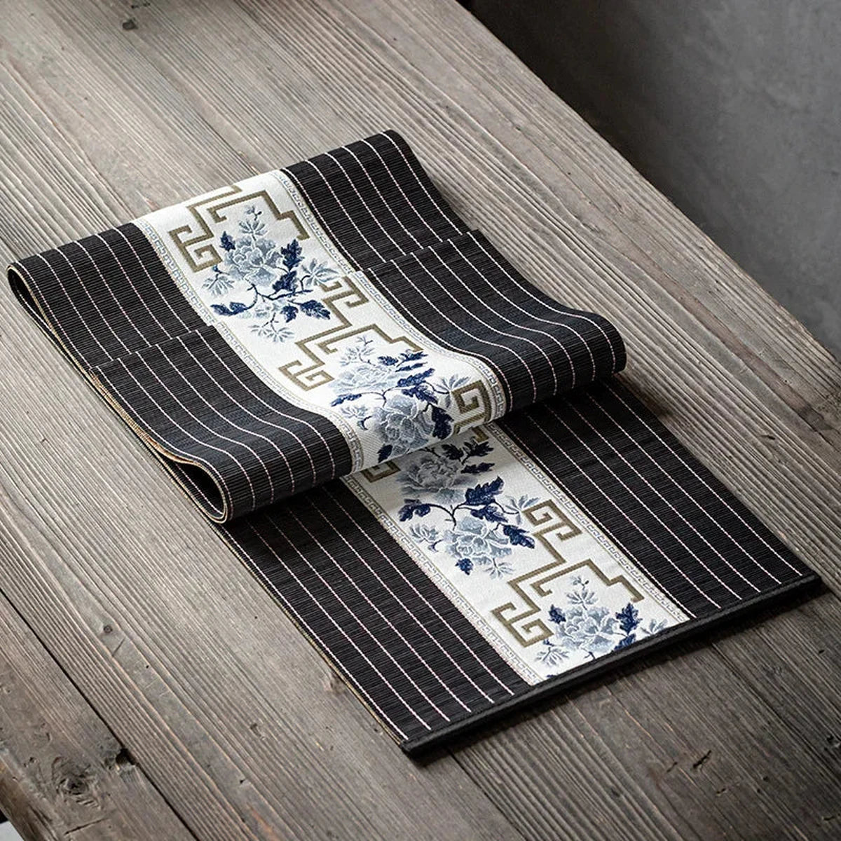 Chemin de table en bambou noir à bandeau blanc porcelaine, sur une table en bois