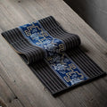 Chemin de table en bambou noir à bandeau bleu porcelaine, sur une table en bois