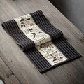 Chemin de table en bambou noir à bandeau fleuri taupe, sur une table en bois