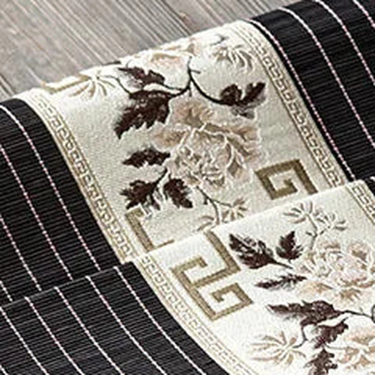 Gros plan de la broderie de fleurs taupe sur bambou noir