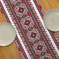 Chemin de table brodé folk rouge et noir sur une table en bois