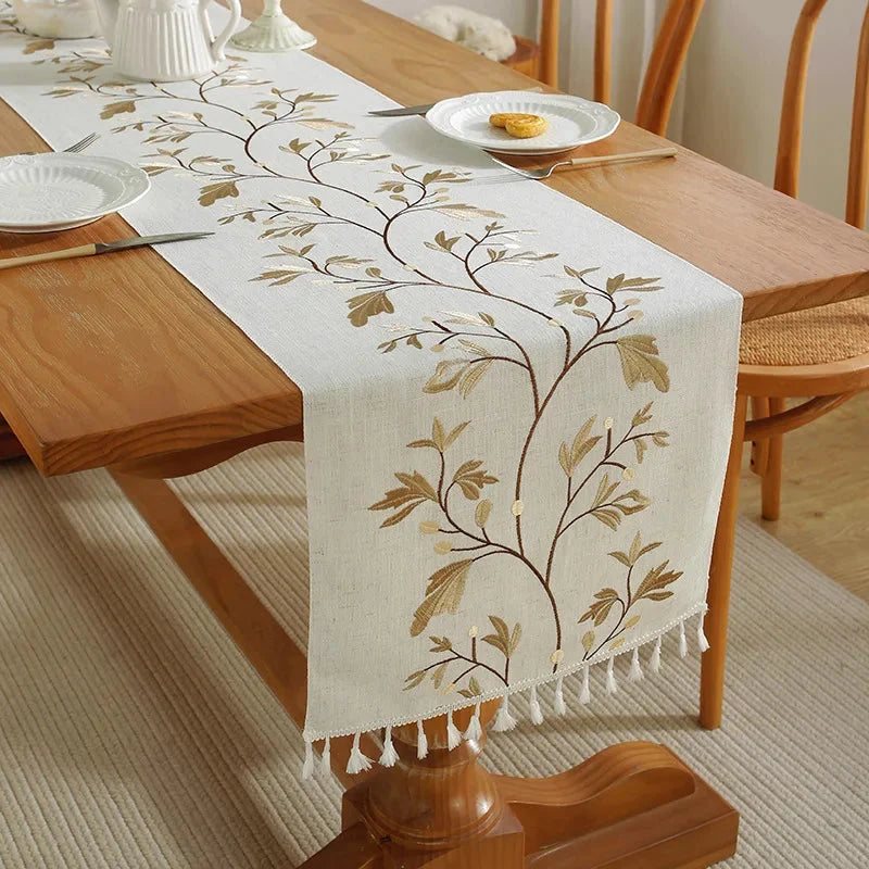 Chemin de table brodé fleurs jaunes à pompons sur une table en bois