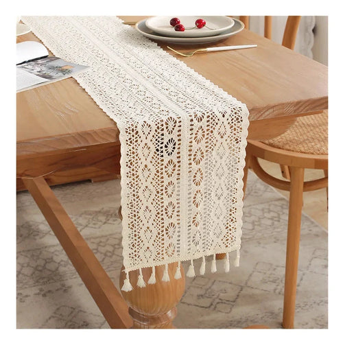 Chemin de table en dentelle au crochet beige à pompons sur une table en bois