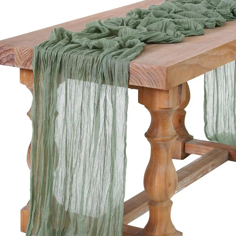 Chemin de table en gaze de coton vert sauge drapé sur une table en bois