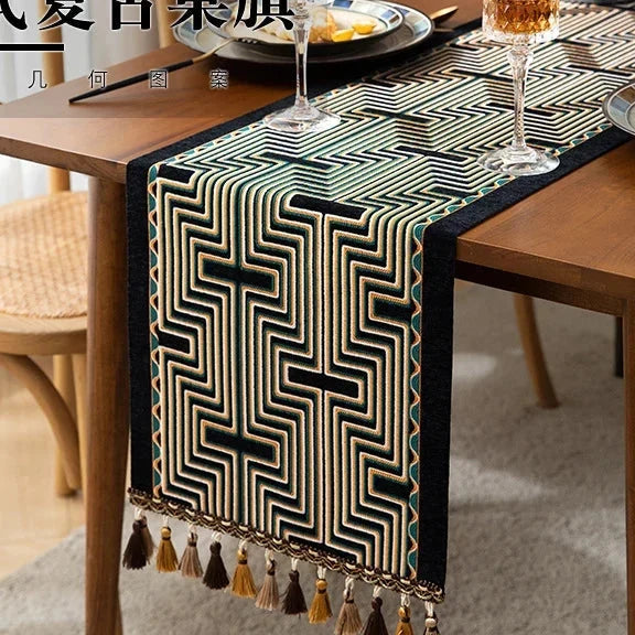 Chemin de table jacquard arabesque noire et dorée à pompons sur table en bois