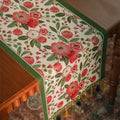 Chemin de table jacquard camélias rouges et bordure verte sur table en bois