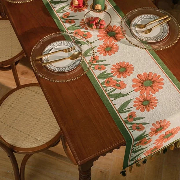 Chemin de table jacquard à fleurs orange et pompons dans une salle à manger