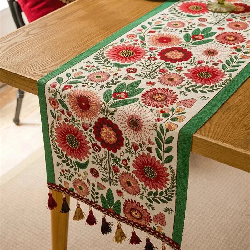 Chemin de table jacquard fleurs roses à pompons sur une table en bois