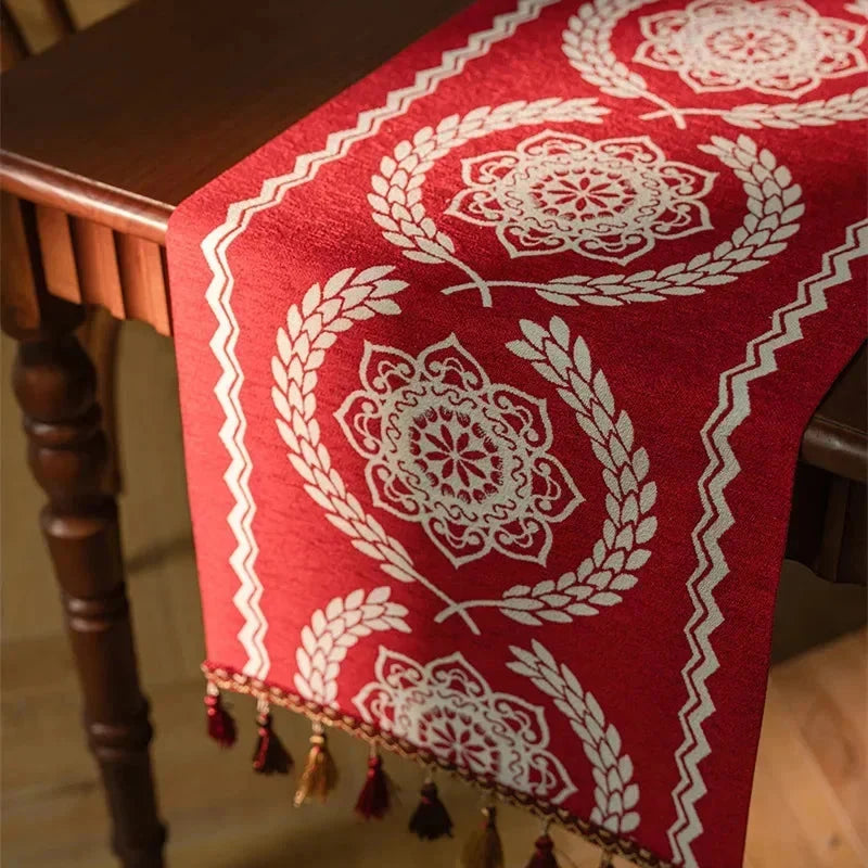 Chemin de table jacquard rouge à médaillons et lauriers drapé sur le bord de table