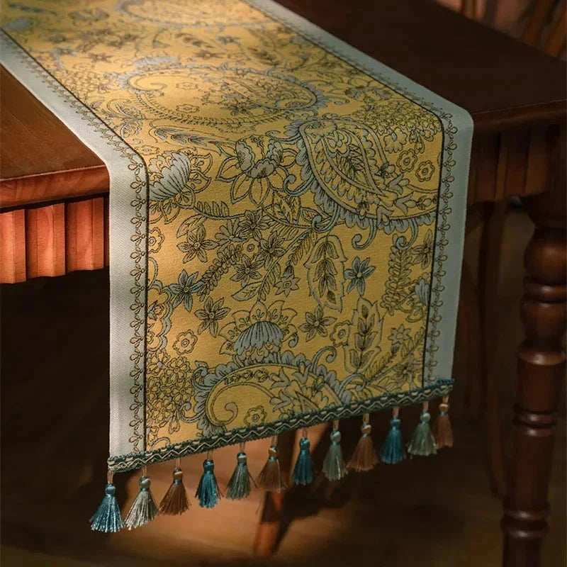 Chemin de table jacquard plumes dorées — drapé aux pompons turquoise