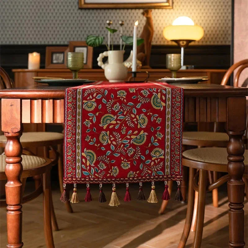 Chemin de table jacquard rinceaux rouges à pompons dans un salon rétro