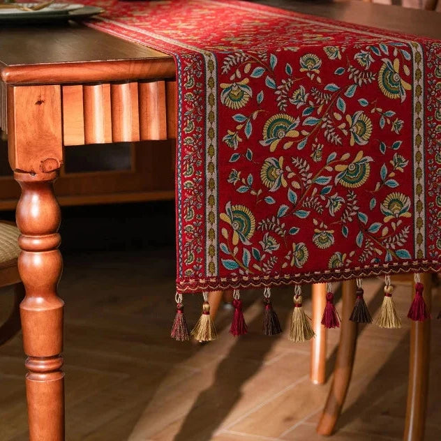 Chemin de table jacquard rinceaux rouges drapé sur une table en bois
