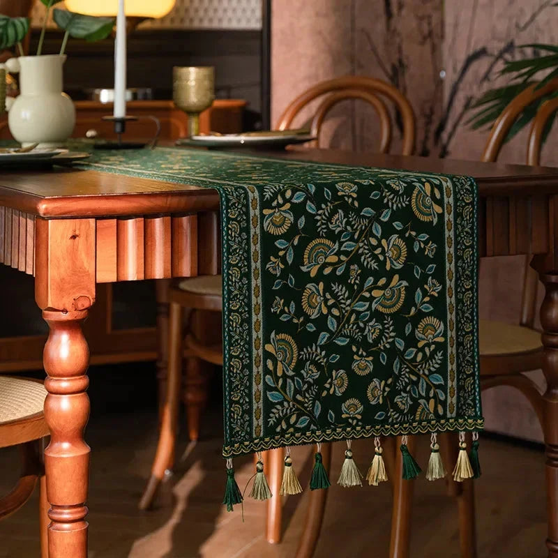 Chemin de table jacquard rinceaux verts et dorés à pompons dans un salon rétro