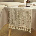 Chemin de table en macramé crème à pompons drapé sur une table