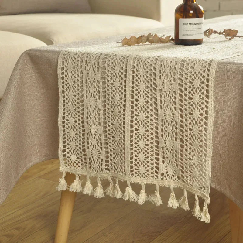 Chemin de table en macramé crème à pompons drapé sur une table