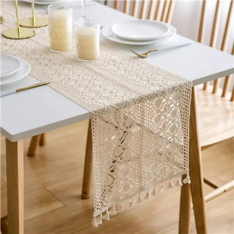 Chemin de table macramé crème à pompons sur une table blanche