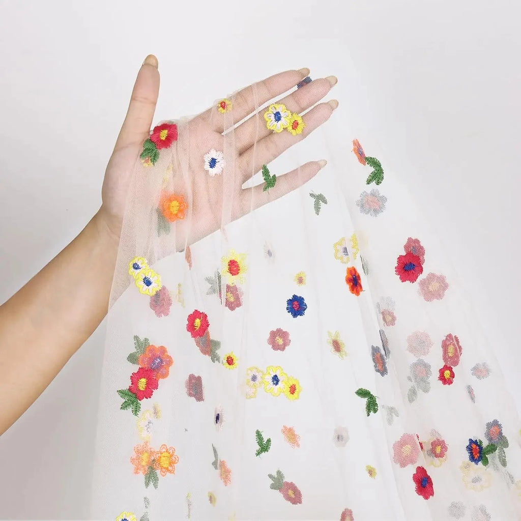 Détail des marguerites brodées multicolores du tulle dans une main