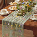 Chemin de table en tulle vert brodé de papillons sur une table de réception