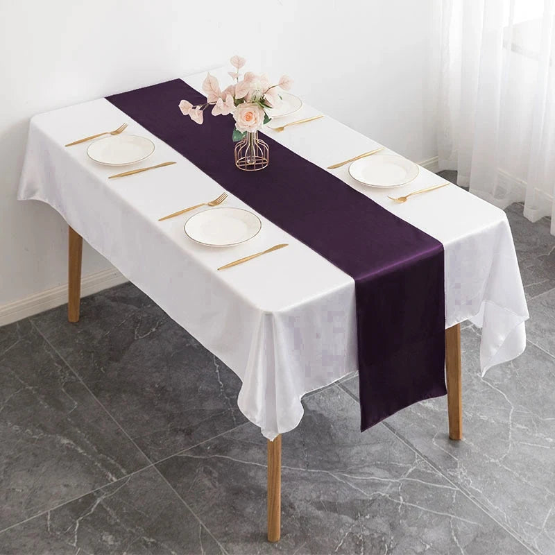 Chemin de table en satin violet prune avec couverts dorés sur table dressée