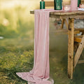 Chemin de table en velours rose poudré drapé sur une table champêtre en bois