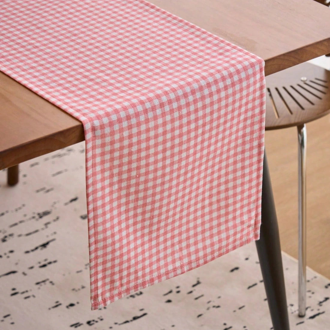 Chemin de table à carreaux vichy rose et blanc drapé sur une table en bois